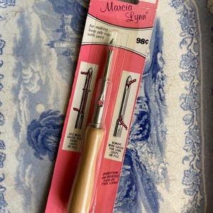 Può includere: Un ago per punzonatura di tappeti vintage di Marcia Lynn, n. 6, per realizzare tappeti a pelo riccio con filato. Lo strumento ha un manico in legno e un ago in metallo, confezionato su una scheda rosa con istruzioni e illustrazioni. Prodotto negli Stati Uniti.
