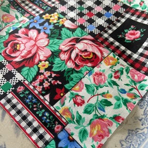 Op de afbeelding: Een vierkante stoffen lap met een patchworkontwerp van verschillende patronen. Het textiel toont grote roze rozen op zwarte en witte achtergronden, afgewisseld met zwart-wit geblokte vierkanten en bloemenprints met blauwe en rode accenten.
