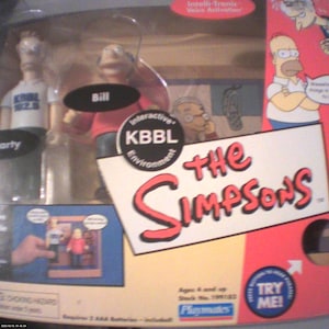 May include: The Simpsons interactive KBBL environment playset in original packaging. Includes action figures of Marty and Bill wearing KBBL 102.5 shirts. The box features the show logo, Intelli-Tronic voice activation, and a Try Me button.