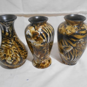 May include: Three decorative ceramic vases with a tiger stripe pattern in shades of brown, black, and tan. The vases have a dark rim and a glossy finish. The vases vary in shape and size, suitable for home decor.