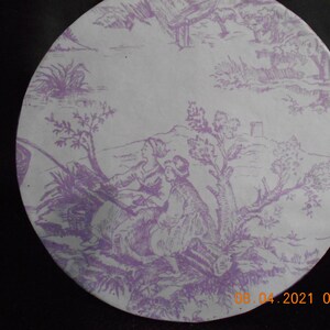 May include: A white ceramic plate with a purple floral pattern. The pattern features a scene of two people in a forest setting. The plate has a scalloped edge.