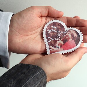 May include: A white heart-shaped card with a photo of a man and a child. The card has the words "So proud of you" written on it.