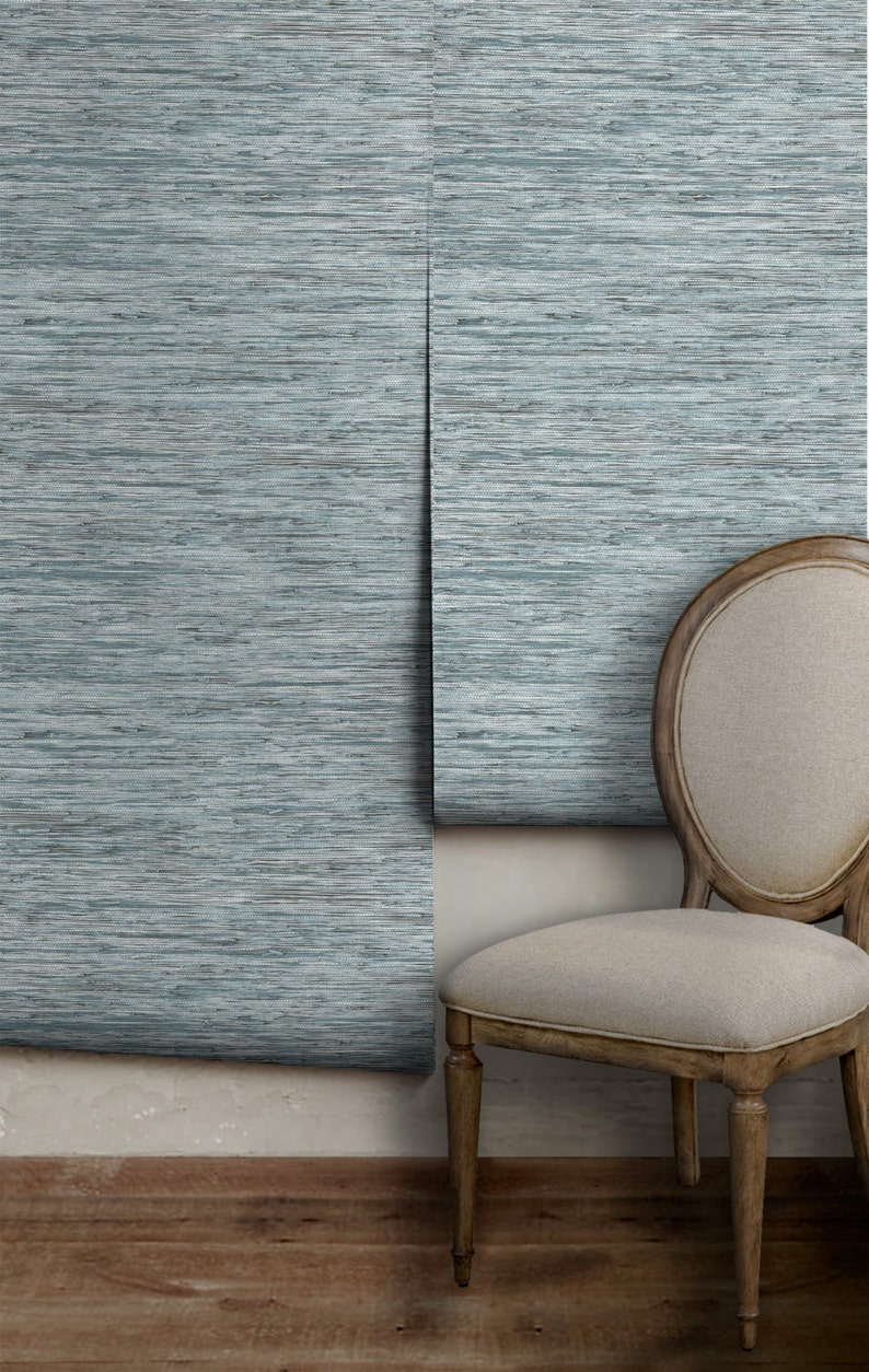 May include: A light blue wallpaper with a woven texture, partially rolled up on a wall. A wooden chair with a light beige fabric seat is in front of the wall.