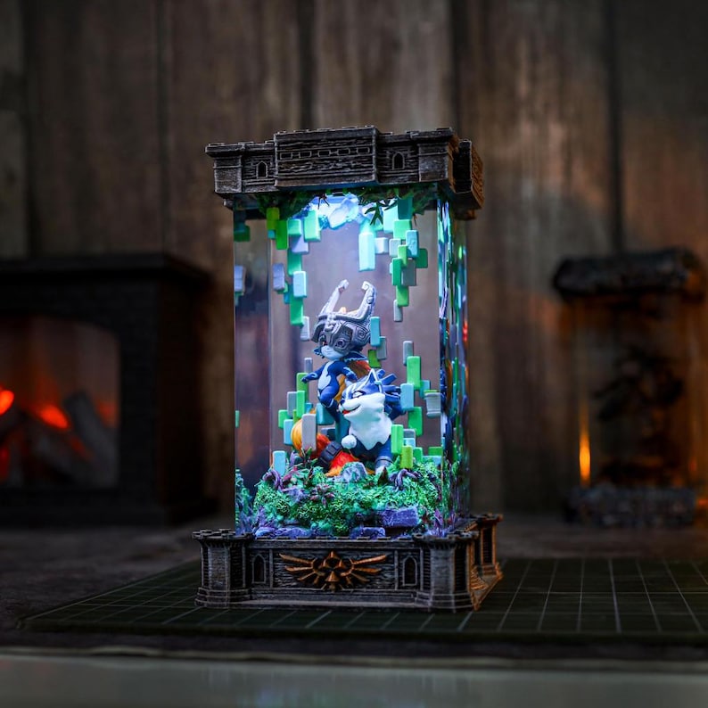 May include: A decorative light-up display featuring video game characters. The display is encased in a rectangular glass structure with a detailed, dark grey base and top. The interior features a colourful scene with pixelated elements and figures.