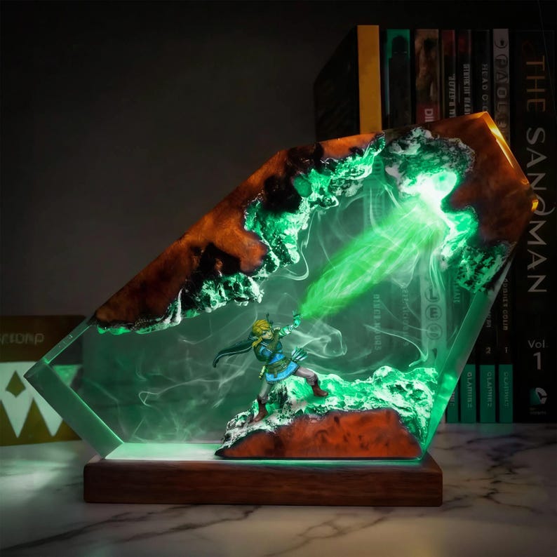 May include: A decorative resin lamp featuring a miniature figure in a dynamic pose, emitting a green energy beam. The lamp has a wooden base and a clear, angled resin body with brown and green accents. The scene is illuminated with green light.
