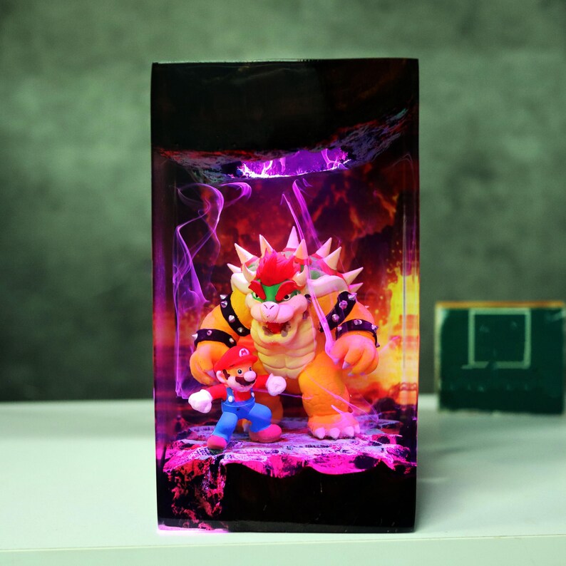 Op de afbeelding: Een rechthoekig harskunstwerk met de personages Bowser en Mario uit de Super Mario-videogame-serie. Bowser is oranje en geel, en Mario draagt zijn klassieke rode en blauwe outfit. De achtergrond heeft paarse en oranje tinten.