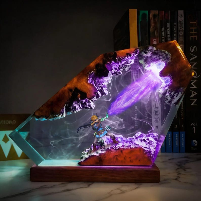 May include: A decorative resin sculpture featuring a miniature figure in a dynamic pose, emitting a purple energy beam. The sculpture has a wooden base and is encased in a clear, angled resin with orange and purple accents. The overall design is illuminated with internal lighting.