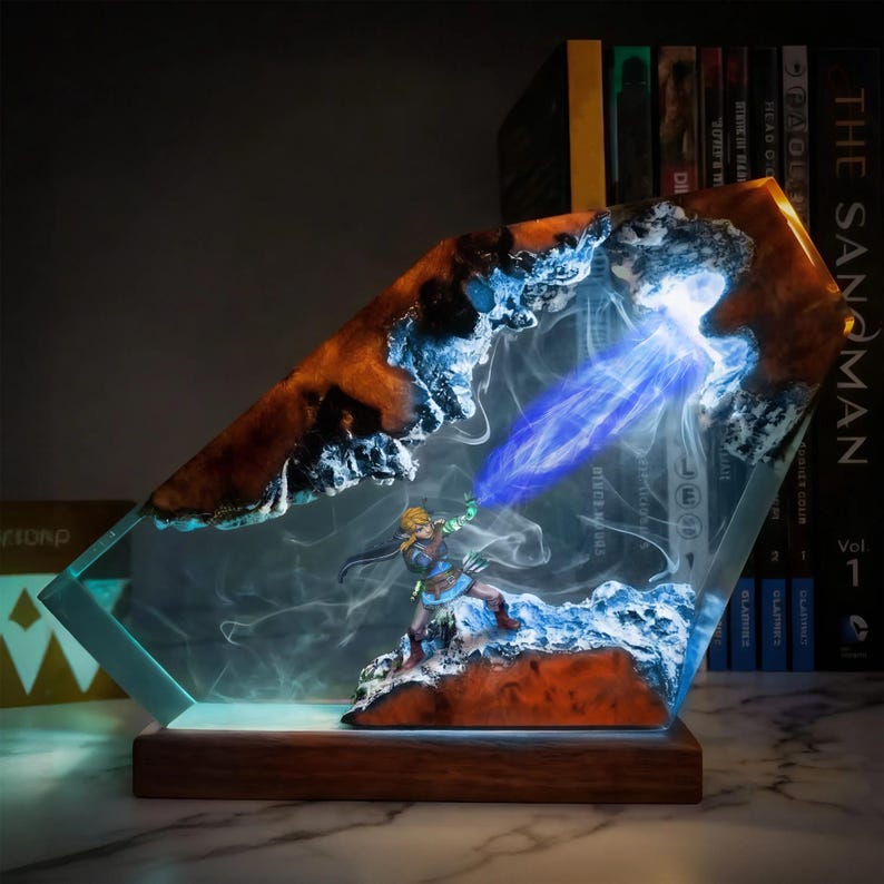 May include: A decorative resin sculpture featuring a miniature figure with a blue energy beam. The sculpture has a wooden base and a clear, angled resin body with orange and blue accents. The figure is in a dynamic pose, suggesting action.