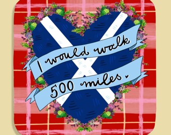 May include: A square coaster with a Scottish flag heart design, surrounded by flowers and the text "I would walk 500 miles." The background is a red and pink plaid pattern.