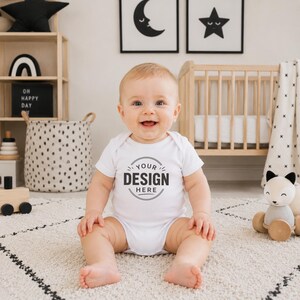 Puede incluir: Un body blanco de manga corta para beb&eacute; con un gr&aacute;fico circular en el pecho que incluye el texto "YOUR DESIGN HERE" en letras negras en negrita. La prenda cuenta con un cuello redondo y cierres de presi&oacute;n en la parte inferior.