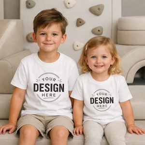 Puede incluir: Dos camisetas blancas de manga corta con un gr&aacute;fico circular en el pecho con el texto "YOUR DESIGN HERE" en letras negras en negrita. Las camisetas tienen cuello redondo y un corte est&aacute;ndar, presentadas como un conjunto a juego.