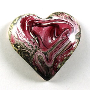 May include: A heart-shaped resin paperweight with a swirling pattern of pink, white, and black paint.