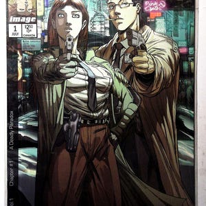 Puede incluir: Portada de cómic de "Darkminds Vol. 1, Capítulo #1: A Deadly Paradox". La obra de arte presenta dos figuras sosteniendo armas, ambientadas en un fondo de ciudad. La portada incluye el logotipo de Image Comics y el texto "Pink Opter."