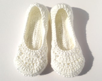 May include: A pair of ivory-colored, crocheted slippers. The slippers have a rounded toe and a textured, openwork design on the top and sides. The interior is a solid, ribbed knit. The slippers are designed to be worn indoors.