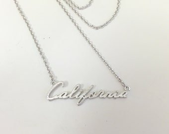 May include: Silver necklace with a cursive 'California' pendant.
