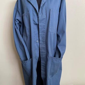 May include: A long-sleeved, blue work coat with a button-up front and multiple pockets.