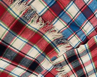May include: A red, blue, and white plaid throw blanket with fringe on the edges.