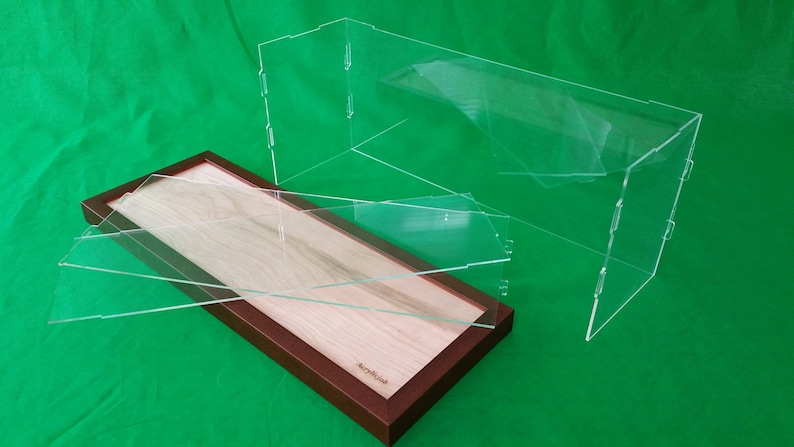 Op de afbeelding: Een rechthoekige houten vitrine met een transparant acryldeksel. De vitrine heeft een lichte houtkleur en een donkerbruine lijst. Het deksel bestaat uit twee scharnierende acryldelen.