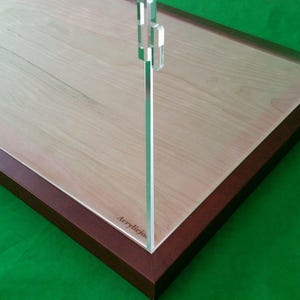 Op de afbeelding: Een vitrine met een licht houten interieur en een donkerbruin frame. De heldere acryl voorkant is bevestigd met een zilveren scharnier. De vitrine staat op een groene ondergrond. Het woord "Acrylicjos" staat op het acryl gedrukt.