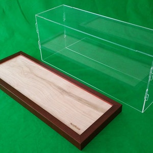 Op de afbeelding: Een transparante acryl vitrine met een houten basis. De vitrine heeft twee planken en is perfect voor het tentoonstellen van verzamelobjecten of andere kleine voorwerpen.
