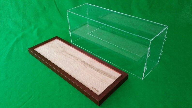 Op de afbeelding: Een transparante acryl vitrine met een houten basis. De vitrine heeft twee planken en is perfect voor het tentoonstellen van verzamelobjecten of andere kleine voorwerpen.