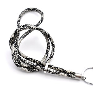 Könnte beinhalten: Ein schwarz-weiß gemustertes Lanyard mit einem silbernen Schlüsselring.