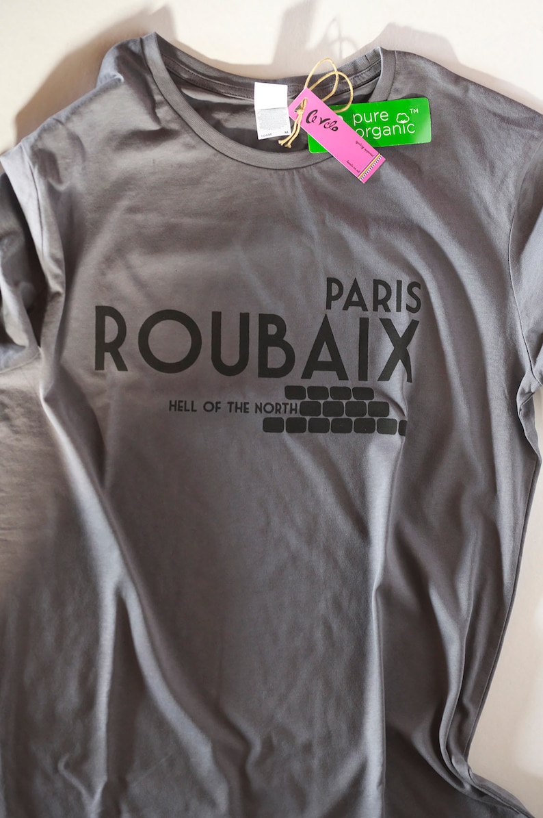May include: Grey t-shirt with black text that reads "Paris Roubaix Hell of the North". The shirt has a green tag that says "pure organic".