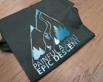 May include: A dark green t-shirt featuring a white outline of a mountain range and trees. The text "Painful Ascent Epic Descent" is printed in blue on the shirt.