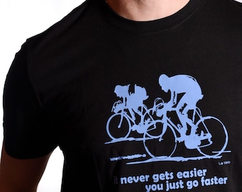 May include: Black t-shirt featuring a blue graphic of three cyclists riding bicycles. The text "it never gets easier you just go faster" is printed below the graphic. The text "Le Velo" is printed in the bottom right corner.