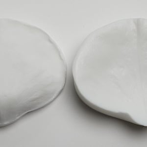 May include: Two white silicone molds for making flower petals. The molds are shaped like petals with a raised vein pattern.