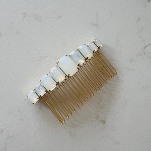 May include: A gold hair comb with a row of white rectangular crystals.