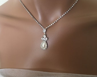 May include: A silver necklace with a teardrop-shaped pendant featuring a faux pearl surrounded by rhinestones.