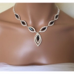 May include: A silver necklace with a teardrop pendant featuring black and clear rhinestones.