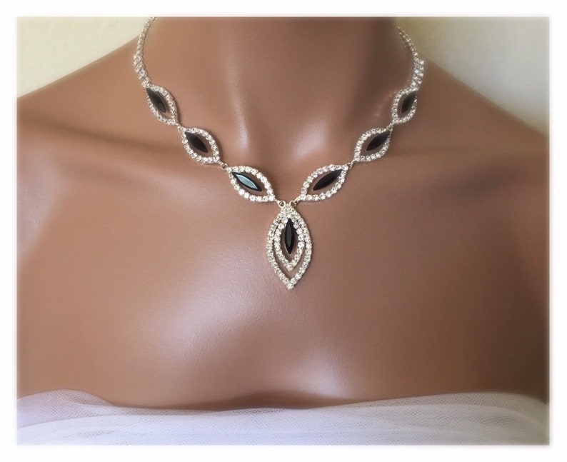 May include: A silver necklace with a teardrop pendant featuring black and clear rhinestones.