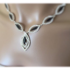 May include: A silver necklace with a black crystal pendant. The necklace is made of small, clear crystals and has a delicate design.