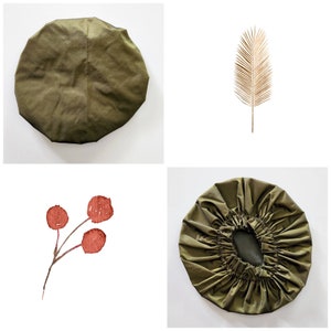 May include: Two olive green shower caps, one with a gathered edge and one with a smooth edge. A watercolor painting of a red berry branch with three berries.