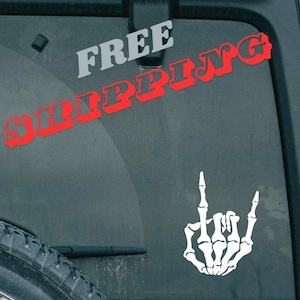 May include: A white skeleton hand making the rock and roll hand gesture. The words "FREE SHIPPING" are in red and gray letters on the background.