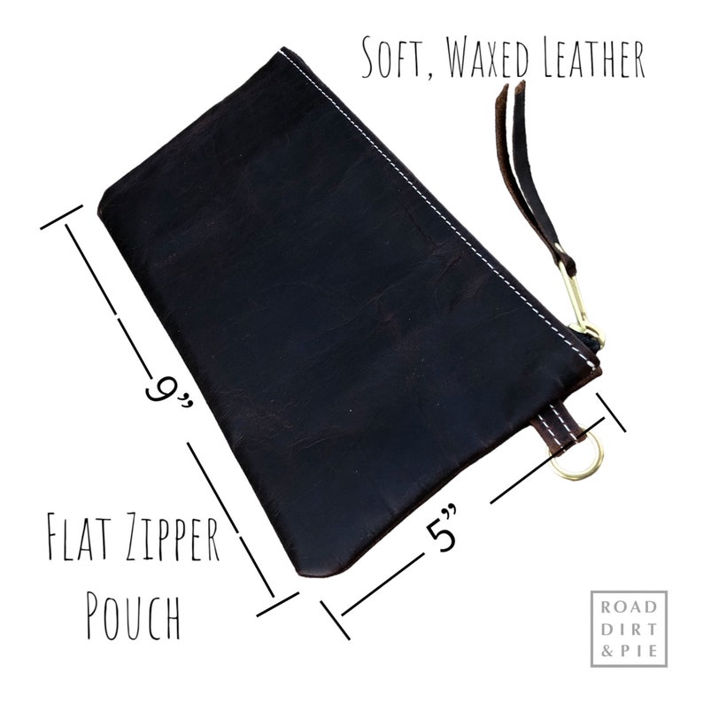 A dark brown leather zipper pouch with white stitching. The pouch is 9 inches long and 5 inches wide. The text 'SOFT, WAXED LEATHER' is printed in white at the top of the image. The text 'FLAT ZIPPER POUCH' is printed in white at the bottom of the image. The text 'ROAD DIRT & PIE' is printed in white at the bottom right corner of the image.