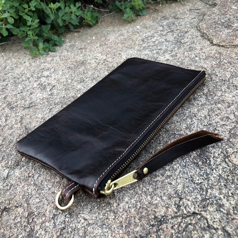 Luxury leather flat zipper pouch with solid brass hardware and an optional wrist strap. Handcrafted in a tiny workshop on wheels near Elephant Rock, in Colorado. This is a limited offering. Made in the USA.