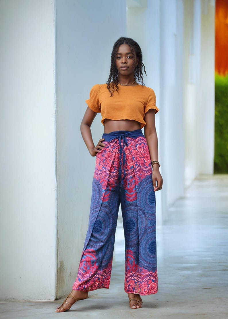May include: A woman wearing a mustard yellow crop top and blue and pink patterned pants with a mandala design. The pants have a tie at the waist.