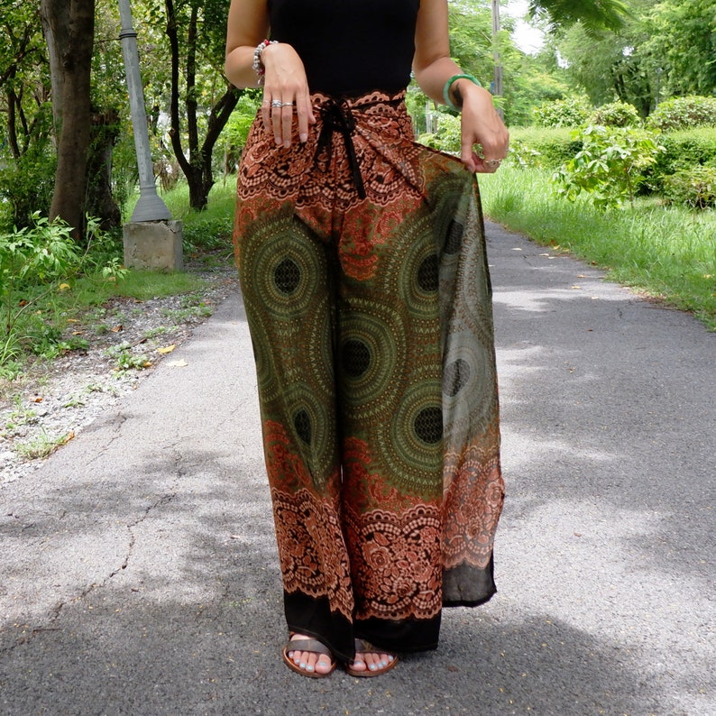 May include: Green and orange printed wide-leg pants with a black waistband and a tie detail. The pants have a flowing, bohemian style.