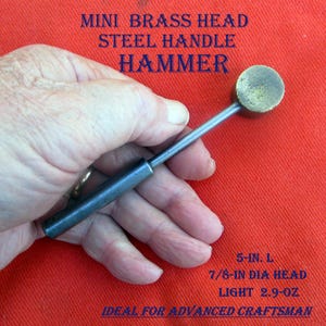 May include: A mini hammer with a brass head and steel handle. The text on the image reads "MINI BRASS HEAD STEEL HANDLE HAMMER". The hammer is 5-in. long with a 7/8-in diameter head and weighs 2.9 oz. The hammer is held in a hand.
