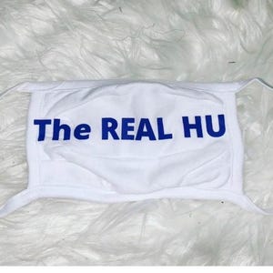 May include: White face mask with blue text that reads "The REAL HU".