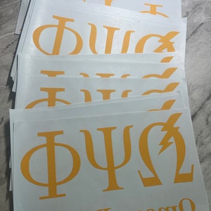 May include: A stack of white vinyl stickers with gold Greek letters. The letters spell out "Phi Psi Omega" and include a lightning bolt symbol.