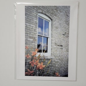 Fotografía original de nubes reflejadas en una ventana de un edificio histórico