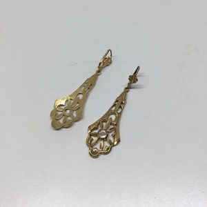 May include: A pair of gold filigree earrings with a clear stone in the center of each earring.