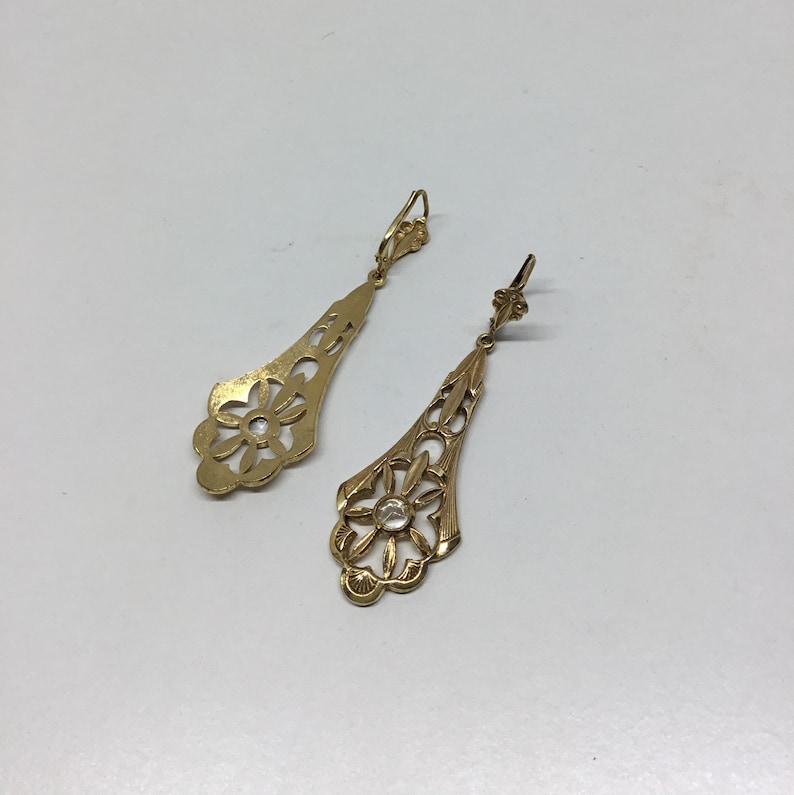 May include: A pair of gold filigree earrings with a clear stone in the center of each earring.