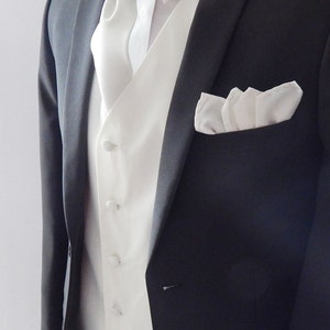 Puede incluir: Una chaqueta de traje negra con un chaleco blanco y una pajarita blanca. La chaqueta de traje tiene un pañuelo de bolsillo blanco.