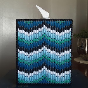 May include: A blue, green, white, and black tissue box cover with a geometric pattern. The cover is made of fabric and has a woven texture.