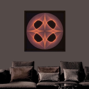 May include: A framed abstract art print with a geometric design in orange and white on a black background. The print is hanging on a grey wall above a brown sofa with cushions.